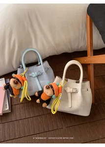 Detail of light blue and beige bucket bags featuring adorable puppy charms and metal buckles