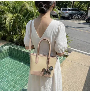Vista detallada del bolso de lona y cuero con colgante de caballo en una modelo femenina