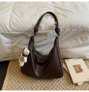 Close-up of deep brown tote bag with knot strap detail and cute teddy bear charm