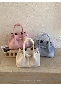 Detailed view of bucket bags in pink, white, and blue with woven texture and leather straps