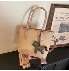 Detalle del bolso saco de lona con adornos de cuero y colgante decorativo de caballo