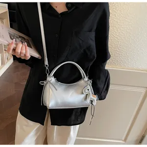 Close-up of metallic silver crossbody bag featuring a horse charm on a leather handle