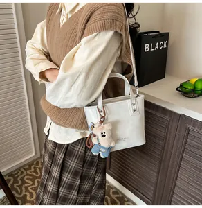 Détail du sac seau blanc brillant avec clous argentés et charmant ours en peluche