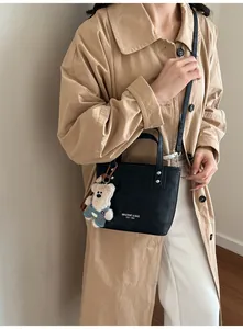 Détail du mini sac cabas noir avec logo blanc et breloque ours en peluche sur bandoulière