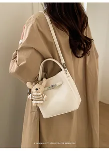 Detail der cremefarbenen Beuteltasche aus Leder mit silbernem Verschluss und Bärenanhänger
