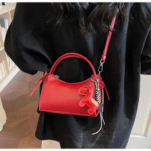 Detail of red faux leather shoulder bag with a cute horse charm and smooth texture