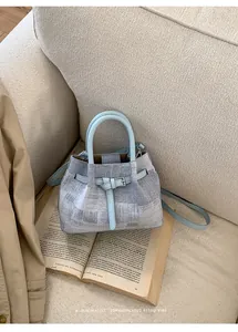 Close-up of a blue and white textured bucket bag on a book with a stylish coat