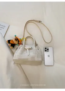 Cream bucket bag with textured fabric, adjustable strap, and cute monkey charm detail