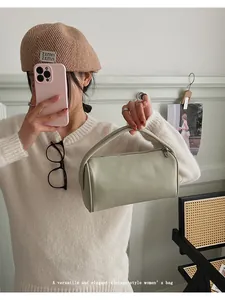 Litchi pattern cylindrical handbag in light green shown with a vintage woven chair