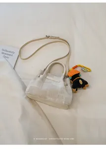 Detail of minimalist cream woven bucket bag with leather trim and cute puppy charm