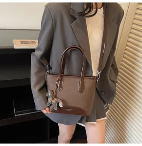 Detalle del bolso de cubo marrón con colgante de caballo de cuero y logo grabado