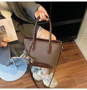 Detalle del bolso de lona y cuero marrón con colgante de caballo y logotipo de marca