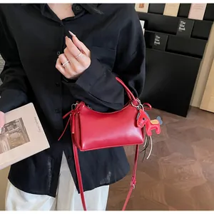 Detailed view of a red soft leather underarm bag with a horse-shaped pendant