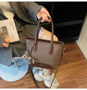 Detalle de bolso tipo cubo marrón con ribete de cuero, colgante de caballo y correa ajustable