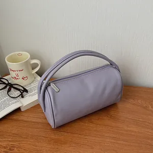 Chic lilac cylinder tote bag in lychee texture leather on a wooden desk setting
