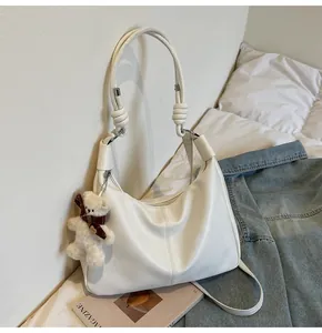 Detail of hobo bag with knotted strap, vertical stitching and cute plush bear charm