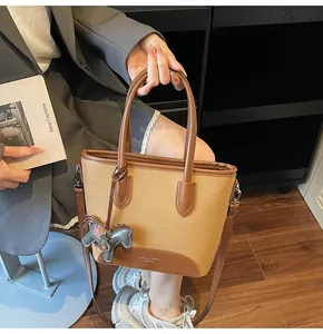 Detalle del bolso de lona y cuero con colgante de caballo llevado por una modelo