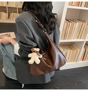 Detail of coffee brown leather tote bag with knot shoulder strap and bear charm decoration