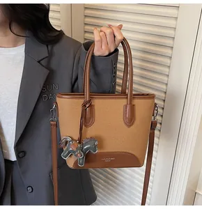 Detalle del bolso de lona con adornos de cuero, colgante de caballo y correa