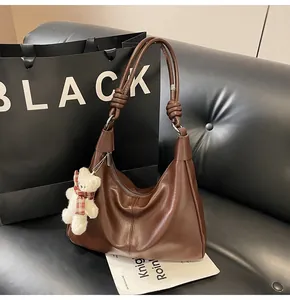 Detail of dark brown leather hobo bag with unique knotted handle and teddy bear charm
