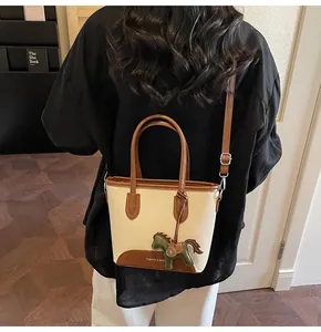 Detalle de bolso bucket de lona con ribete de cuero marrón y colgante de caballo decorativo