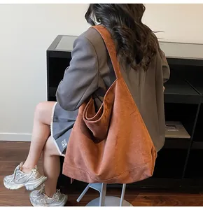 Detail of soft brown suede tote bag with wide shoulder strap showing texture and drape