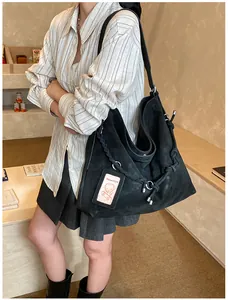 Detail of black suede hobo bag featuring woven rope strap and chic metallic ring accents