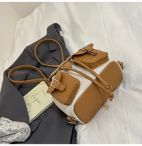 Detalle de mochila de lona con acabados en cuero marrón y dos bolsillos en cama