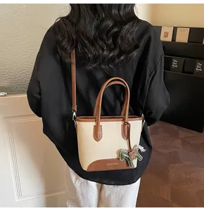 Detalle del bolso de lona con ribetes de cuero y amuleto de caballo en un modelo