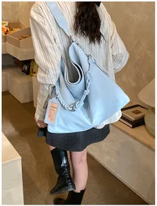 Detail of light blue leather tote bag with braided knot strap and hanging brand tag