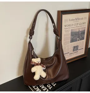 Close-up of coffee brown matte leather hobo bag with teddy bear charm and seam detail