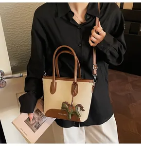 Detalle de bolso cubo de lona con ribete de cuero y colgante de caballo en modelo
