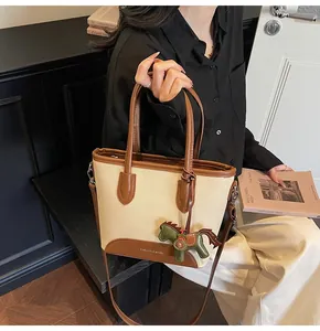 Detalle del bolso de lona con adornos de cuero, logo impreso y colgante de caballo verde