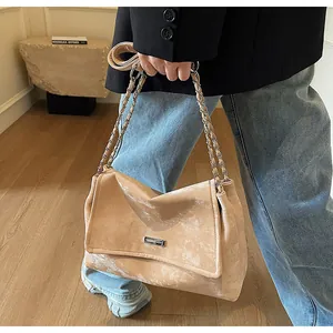 Détail du sac à chaîne en cuir mat marron clair avec ornements argentés sur blazer