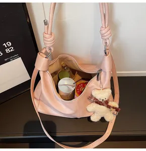 Spacious pink hobo bag detail with knotted strap, plush bear charm, and interior items