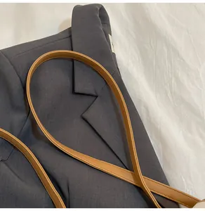 Primer plano de un traje gris oscuro con una delgada correa de hombro de cuero sintético