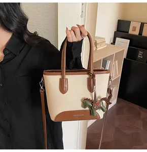 Detalle de bolso cubo de lona con ribete de cuero y colgante decorativo de caballo