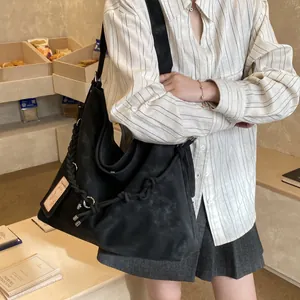 Large black matte tote bag with woven strap detail in a cozy cafe setting