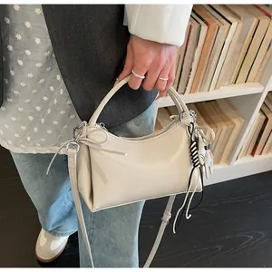 Close-up of minimalist cream leather bag featuring a cute cat charm and bow detail