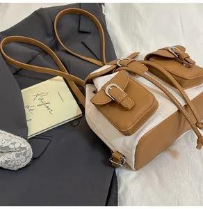 Detalle de una elegante mochila de lona crema con solapas y bolsillos de cuero marrón