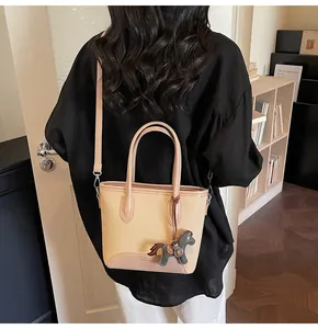 Detalle de bolso cubo de lona con ribete de cuero marrón y colgante de caballo en modelo