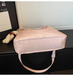 Detail view of pink leather tote bag with soft texture and cute teddy bear charm