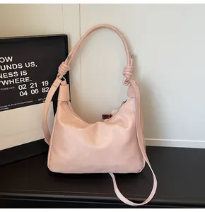 Detail of pink hobo shoulder bag featuring knotted strap and textured leather finish