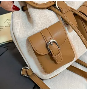 Primer plano de mochila con lona texturizada, ribete de cuero marrón y hebilla metálica