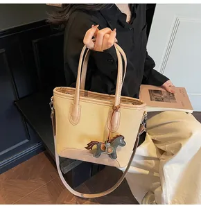 Detalle de bolso saco de lona beige con ribetes de cuero y colgante de caballo en madera