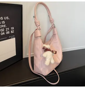 Detail of soft pink faux leather tote bag featuring a knotted handle and cute bear charm