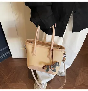Detalle del bolso de lona con adornos de cuero y el colgante decorativo en forma de caballo