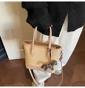 Detalle de bolso tipo cubo de lona con ribetes de cuero marrón y colgante de caballito