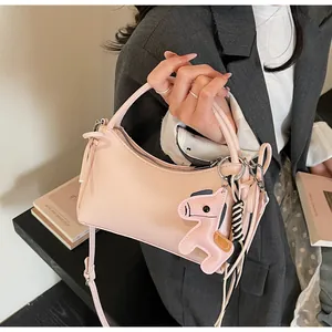 Pink crescent underarm bag with a leather horse charm and adjustable strap detail