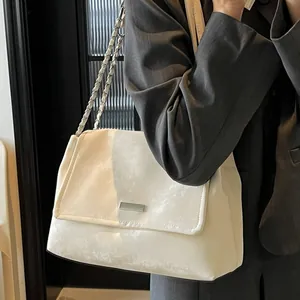 Sac fourre-tout minimaliste en cuir blanc avec chaîne argentée porté par un mannequin